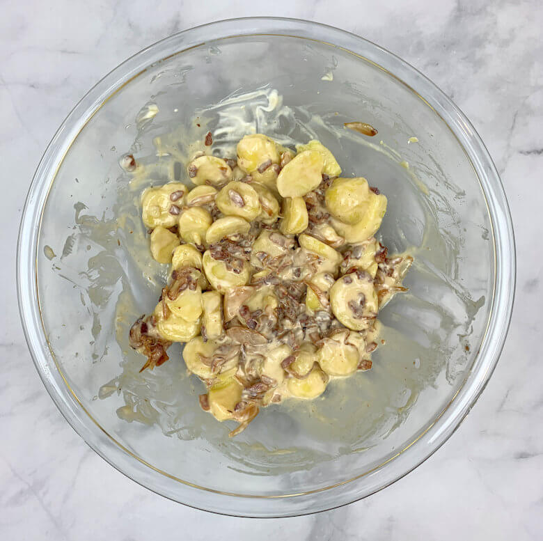 Glass bowl with a mixture of potatoes, creme fraiche, bacon and onion